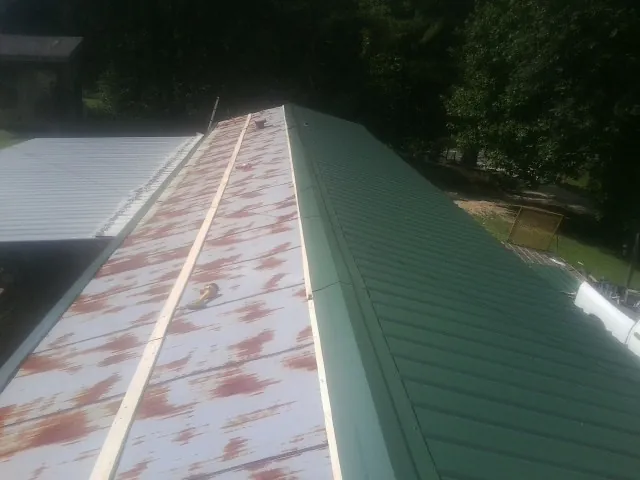 Old rusted panels beside newly installed green metal roofing — Wind Damage Roof Repair by Roofing Brothers in Molena