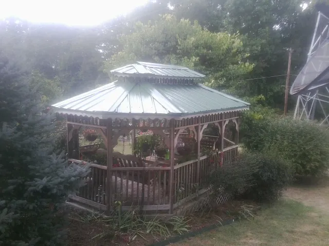 Green metal roof on a backyard gazebo surrounded by garden beds in Molena