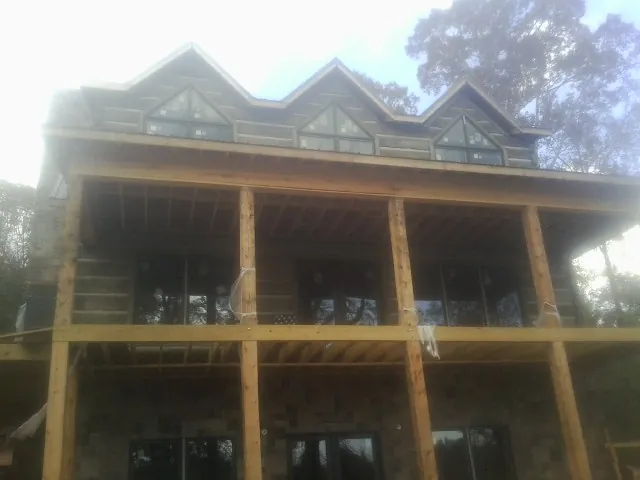 Dormers and porch framing on a large log home under construction — Roof Coating work by our crew in Molena