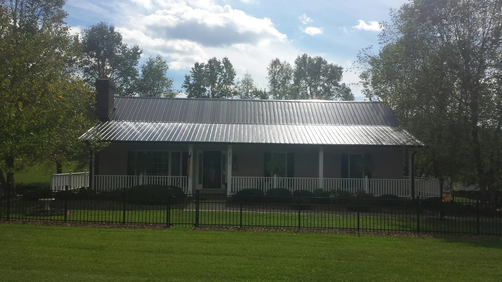 Gray metal roof on a brick ranch with a full width front porch — Gutter Guard Installation work by our crew in Molena
