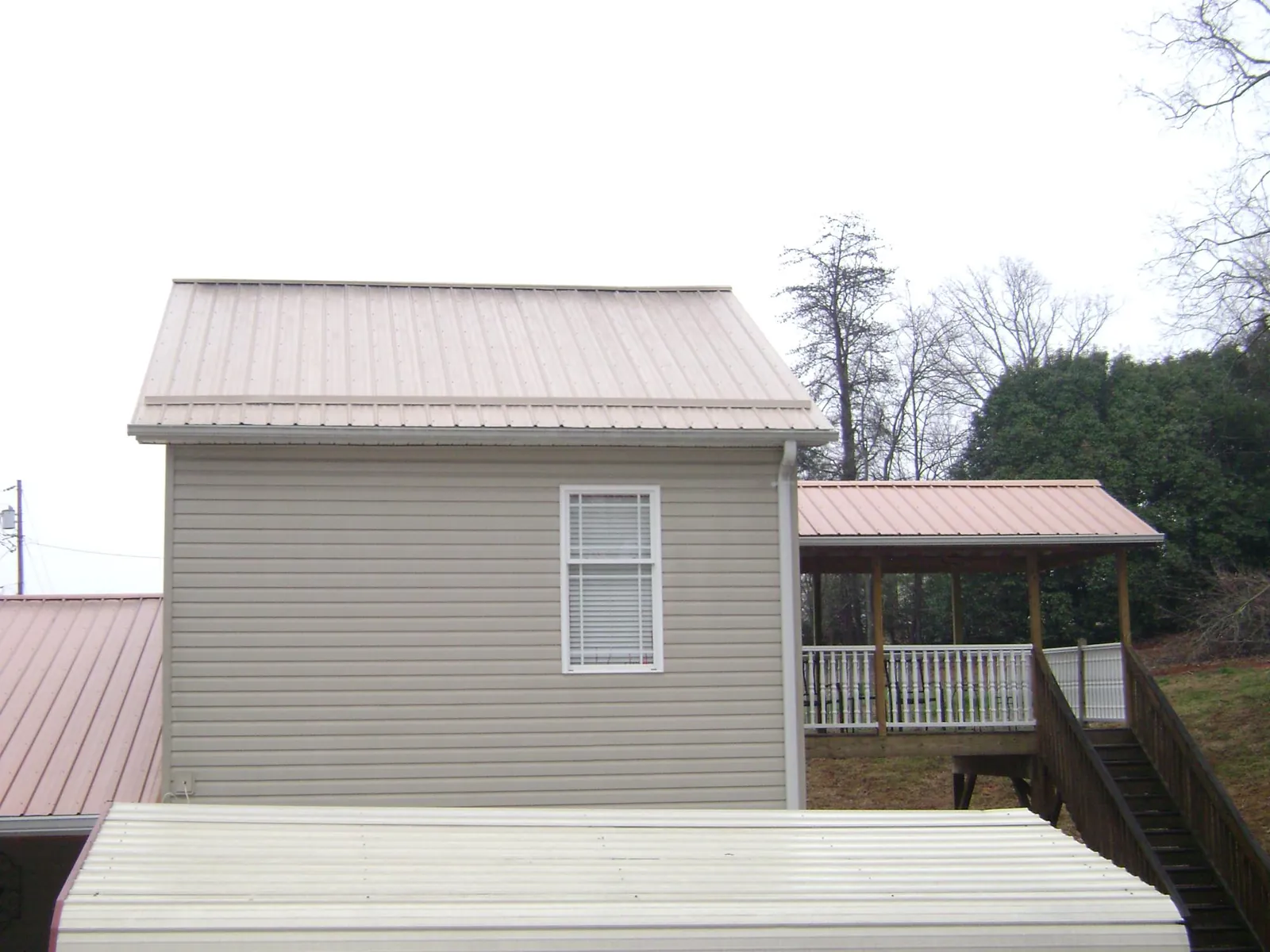 Tan metal roofs on a two story addition and attached porch, from a Roof Replacement job in Molena