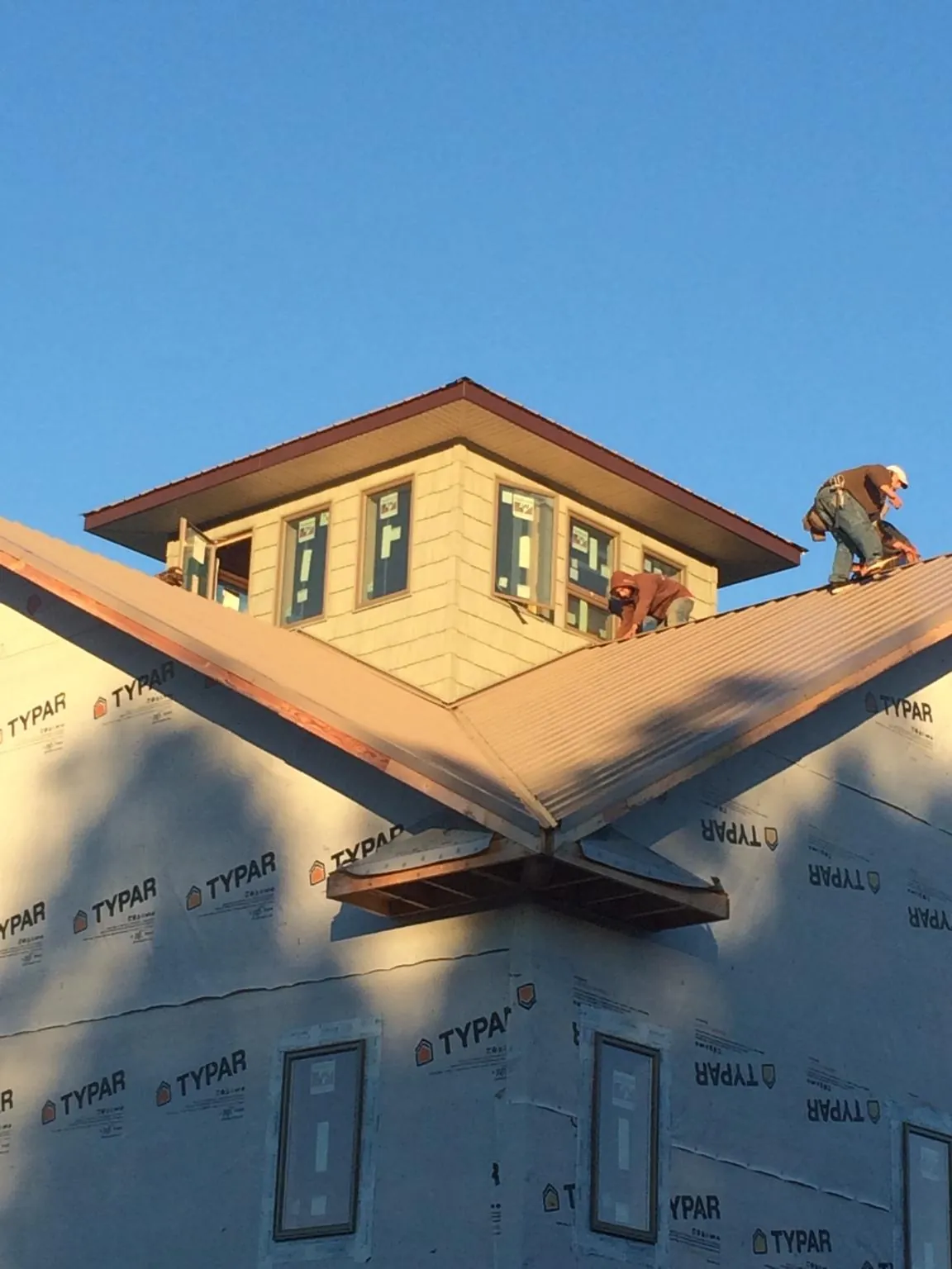 Roofers working around a rooftop cupola on a new metal roof at sunset — Roof Waterproofing in Molena by Roofing Brothers